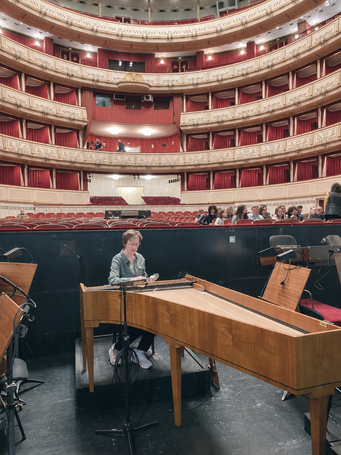Mona Parmentier accordant un pianoforte sur la scène de l'Opéra de Vienne, la salle en arrière-plan