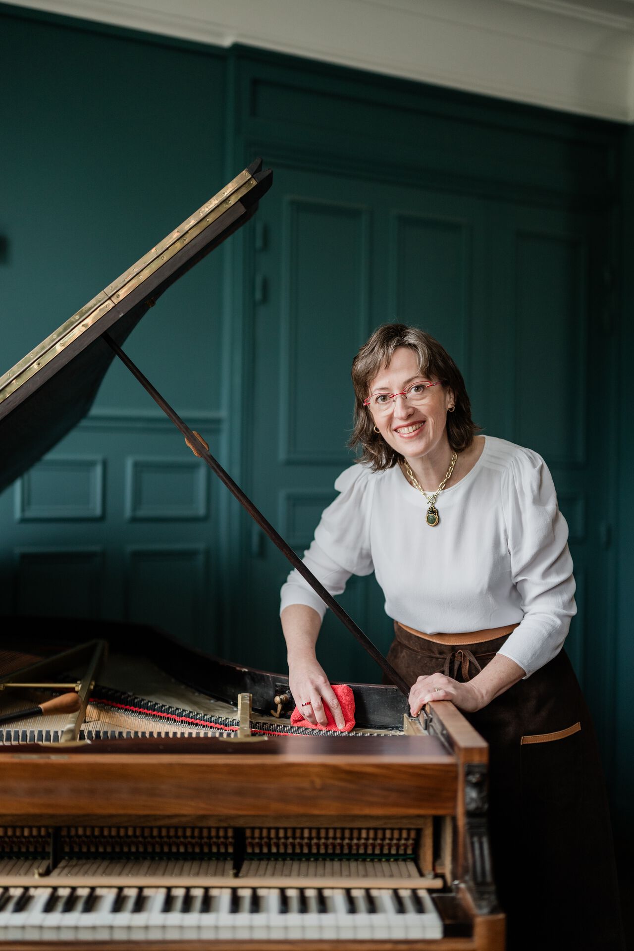 Mona Parmentier nettoyant la table d'harmonie d'un pianoforte
